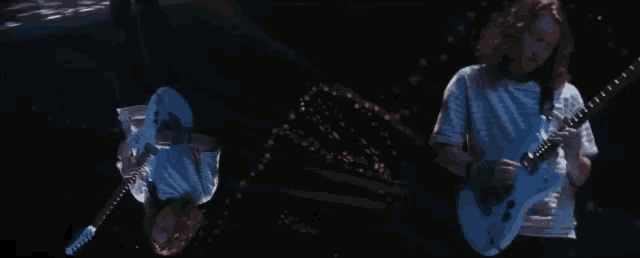 a man with long hair is playing a guitar in the dark