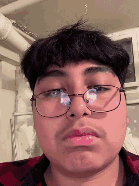 a man wearing glasses and a plaid shirt is making a funny face