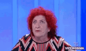 an older woman with red hair is making a funny face while wearing a striped shirt .