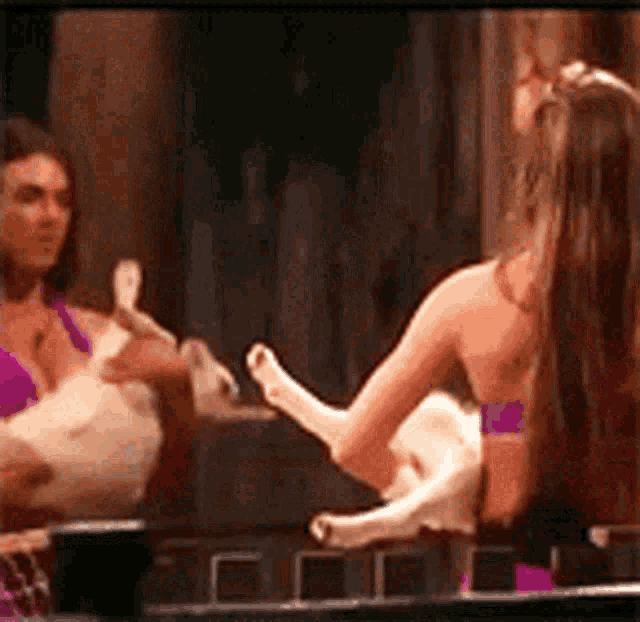 a woman in a purple bra is holding a cat while looking at herself in a mirror .
