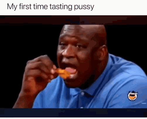 a man in a blue shirt is eating a chicken wing with the caption my first time tasting pussy .