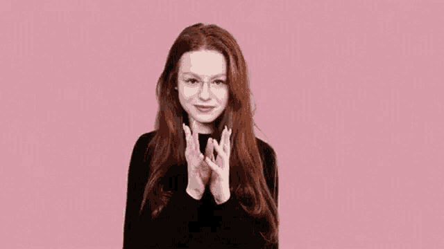 a woman with long red hair is wearing glasses and making a funny face .
