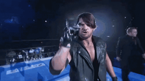 a wrestler is standing in a wrestling ring holding a sword .