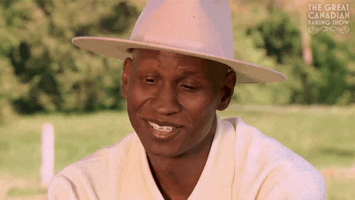 a man wearing a white hat is smiling for the great canadian baking show .