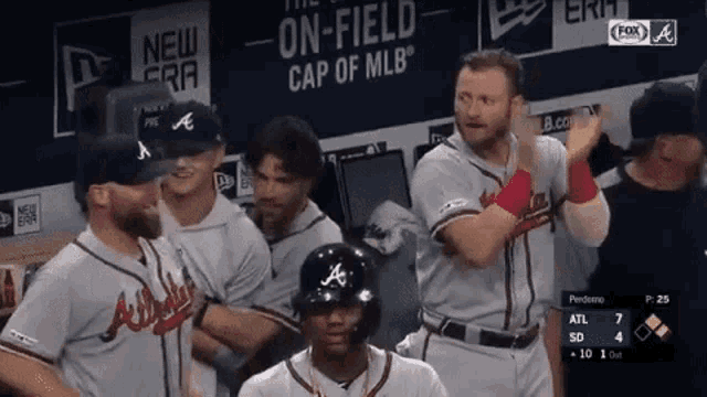 a group of baseball players are standing in a dugout with a sign that says " on-field cap of mlb "