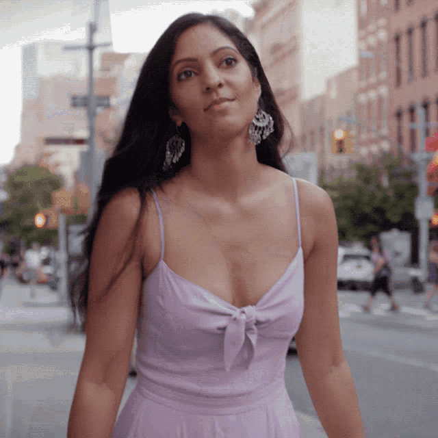 a woman in a purple dress stands on a city street