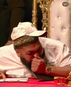 a man with a beard wearing a hat and a watch is laying down on a table .