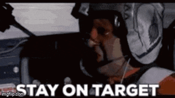 a man in a helmet is sitting in a car with the words `` stay on target '' written on the screen .