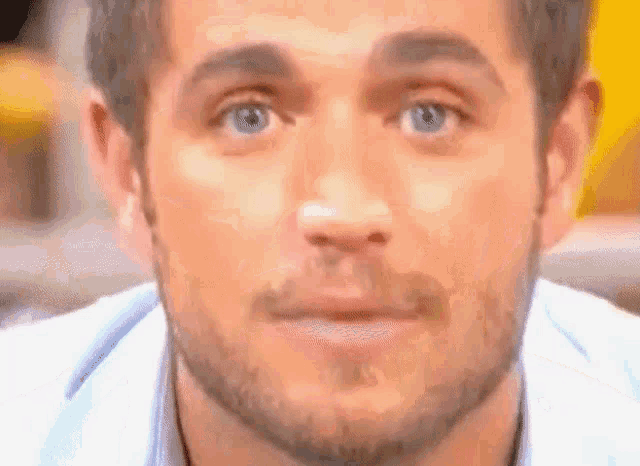 a close up of a man 's face with blue eyes and a beard .