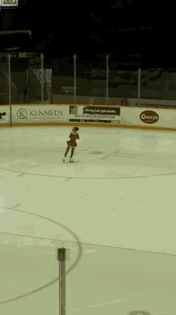 a person ice skating in front of a sign that says kennedy on it