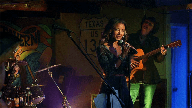 a woman singing in front of a sign that says texas
