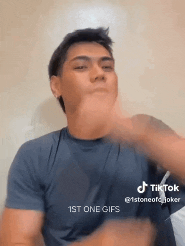 a man in a blue shirt is making a funny face with his hands and says 1st one gifs .