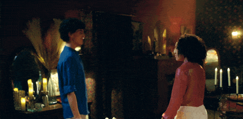 a man and woman are dancing in a room with candles and a mirror