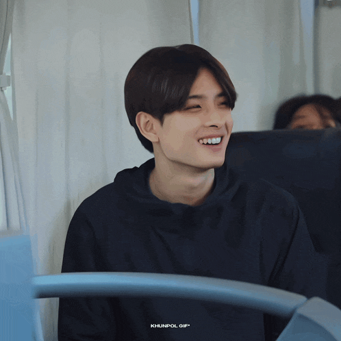 a young man in a black hoodie is smiling in a photo taken by khunpol
