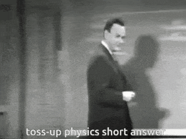 a man in a suit and tie is standing in front of a blackboard and says toss-up physics