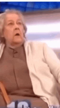 an older woman is sitting in a chair with her mouth open and a surprised look on her face .