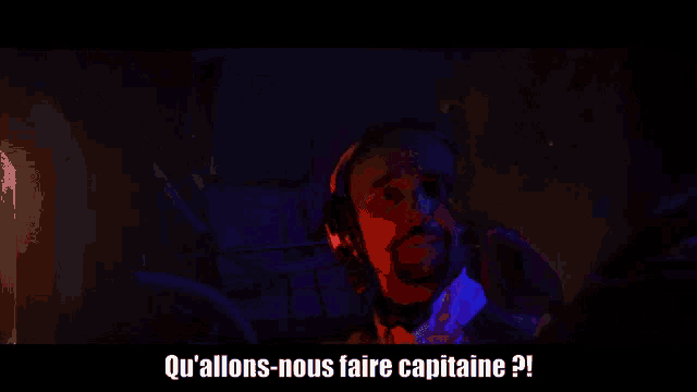 a group of people are standing in a dark room with the words qu'allons-nous faire capitaine