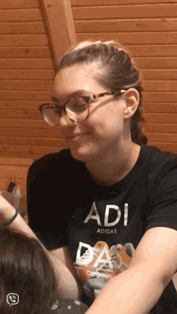 a woman wearing glasses and a black adi adidas shirt
