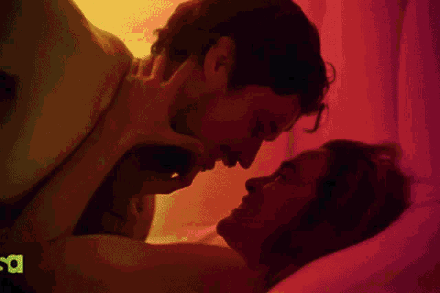a man and a woman are laying on a bed with a green light behind them that says s.a.
