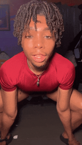 a young man in a red shirt is kneeling down