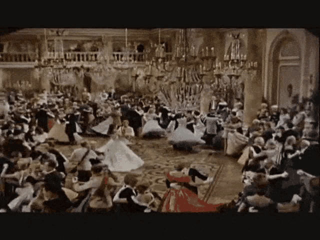a large crowd of people are dancing in a ballroom .