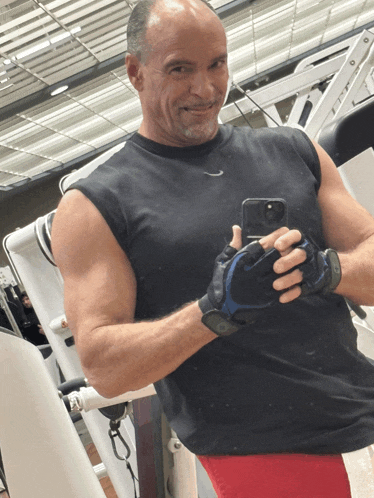 a man taking a picture of himself in a gym with a nike shirt on