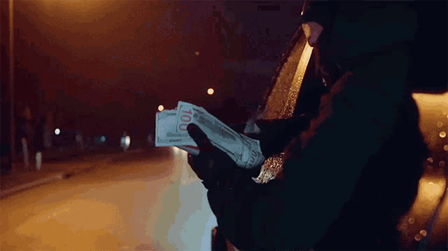 a person holding a stack of 10 dollar bills in their hand