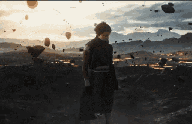 a man is standing in the middle of a field with rocks falling around him