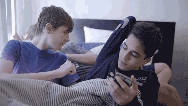 two boys are laying on a bed and one has a shirt that says uio on it