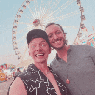 two men posing in front of a ferris wheel
