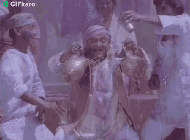 a group of people are dancing in a room with a purple background and a gifkaro logo in the corner