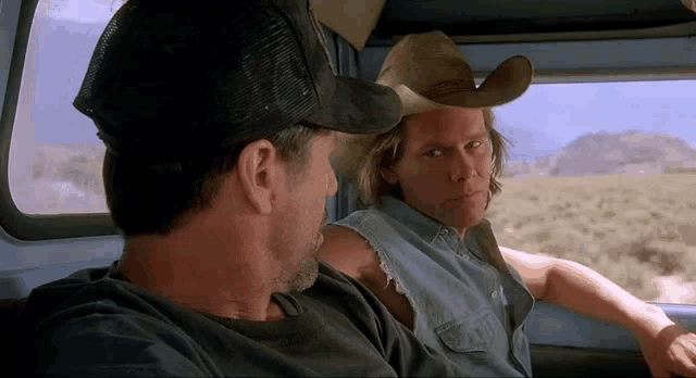 two men wearing cowboy hats are sitting in a car
