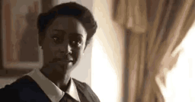 a woman in a maid 's uniform is standing in front of a window .