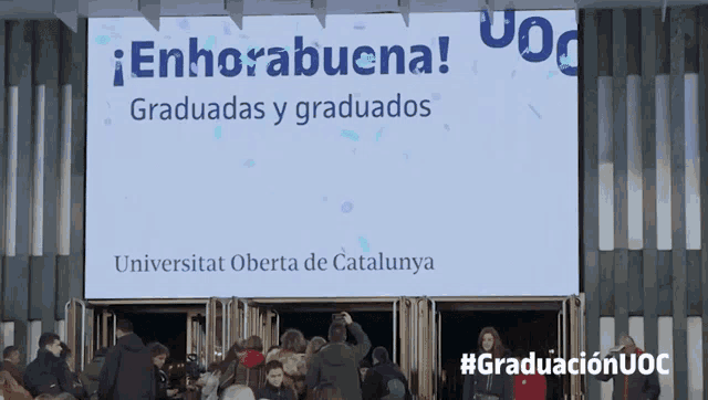 a crowd of people are gathered in front of a sign that says enhorabuena
