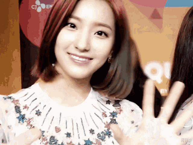 a woman with red hair is smiling and giving a peace sign
