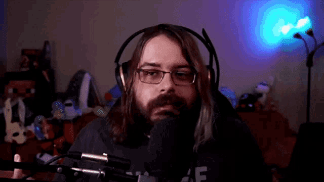 a man with long hair and a beard is wearing headphones and a shirt that says staff