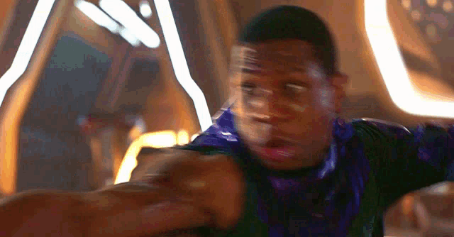 a blurry picture of a man in a purple shirt with his arms outstretched .