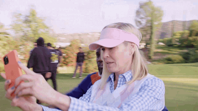 a woman in a pink hat is taking a picture of herself on a golf course