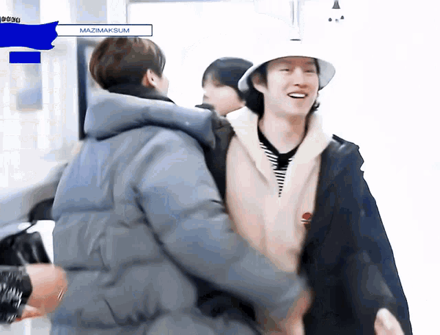 a man wearing a hat is hugging another man in a jacket .