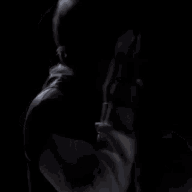 a man wearing a mask is holding a microphone in a dark room .