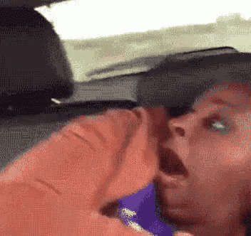a person sitting in the back seat of a car with their mouth wide open