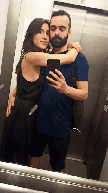 a man is taking a selfie with a woman in an elevator