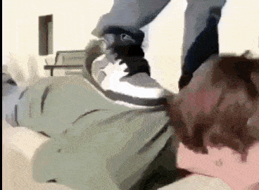 a person is laying on the floor with their feet on another person 's head .