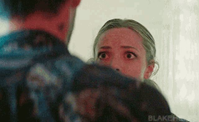 a man and a woman are standing next to each other and the woman is looking at the man 's face .