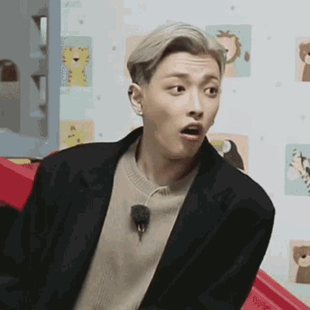a man in a suit and sweater is making a funny face while sitting on a red slide .