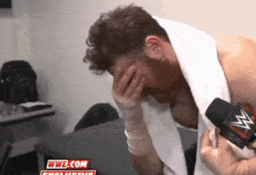 a man with a towel around his neck is being interviewed by a wrestler