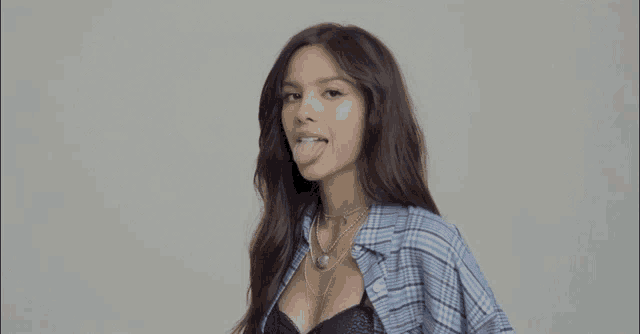 a woman sticking her tongue out while wearing a plaid shirt and bra