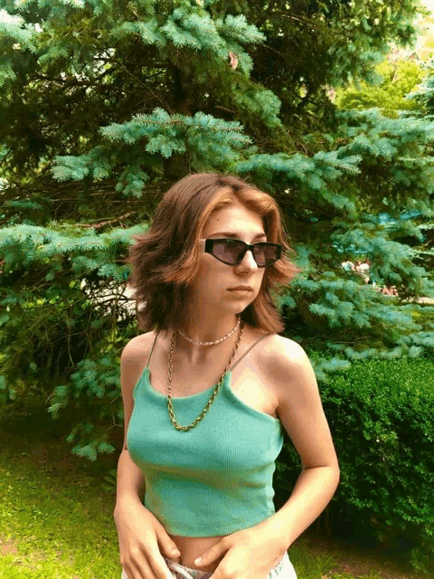 a girl wearing sunglasses and a green tank top