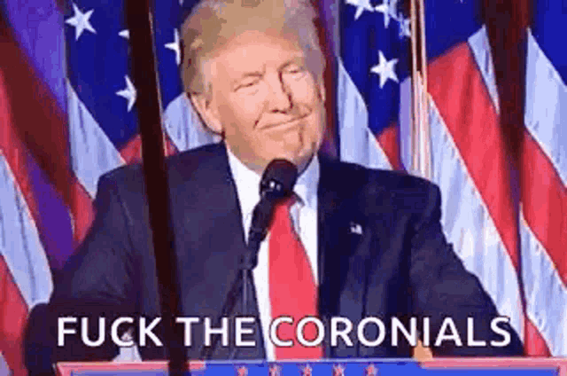 donald trump is giving a speech at a podium in front of an american flag and says `` fuck the colonials '' .