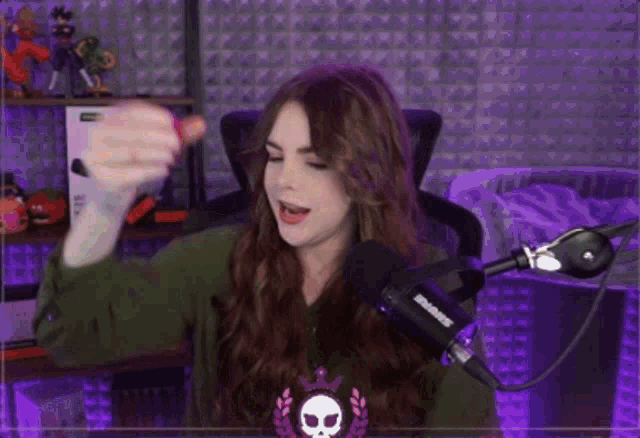 a woman is standing in front of a microphone with a skull on her shirt